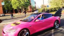 Sergey Brin in Google Glass driving a pink Tesla Batmobile with eyelashes